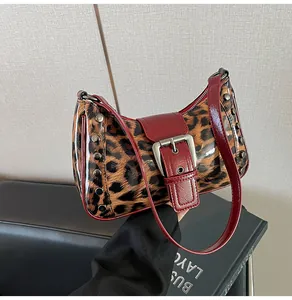Detail of leopard print bag with red leather trim, silver rivets, and large buckle