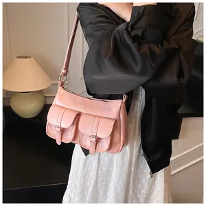 Primo piano della borsa hobo rosa con tasche frontali e fibbie sulla modella
