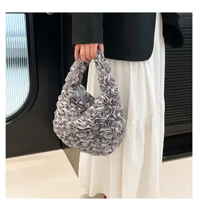 Detailansicht der silbernen Satin-Handtasche mit plissierter Rüschenstruktur und Griff