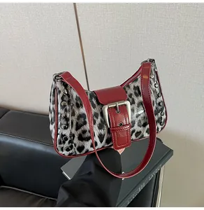 Detailed view of leopard print shoulder bag with red trim and silver metal buckle