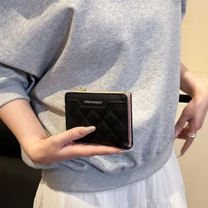 Black quilted leather women's small wallet with gold L-zipper held by a model