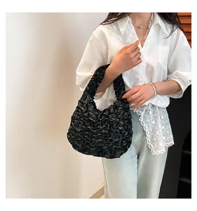 Detail showing the intricate ruffle texture and glossy black fabric of the handbag