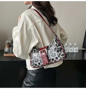 Detailed close-up of leopard print shoulder bag featuring red leather trim and metal rivets