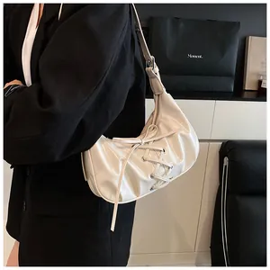 Detail of cream white glossy crescent bag with ribbon laces and adjustable strap