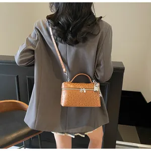 Brown ostrich textured handbag shown on model in a modern interior setting