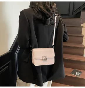 Detail of light beige crossbody bag featuring a polished silver square hollow buckle