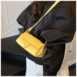 Chic yellow crossbody bag with lychee texture shown on a black coat for a sharp contrast