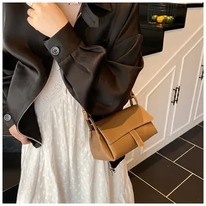 Brown lychee leather crossbody pillow bag shown on model with vertical stitching detail