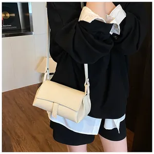 Close-up of minimalist beige lychee grain crossbody bag worn on shoulder by model