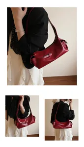 Détail d'un sac sous les bras en cuir ciré rouge foncé avec texture brillante et poches