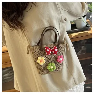 Detailansicht der handgewebten Strohtasche mit Häkelblumen und gepunkteter Schleife