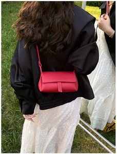Detailed view of red lychee grain leather pillow bag with white contrast stitching