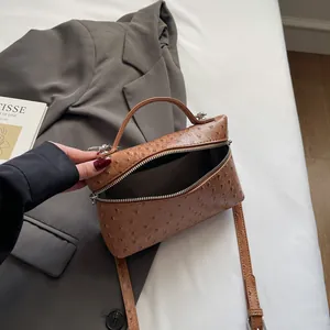 Brown ostrich embossed handbag with top handle and strap shown with open zipper