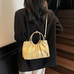 Minimalist beige pleated bucket bag with curved handles and a thin crossbody strap