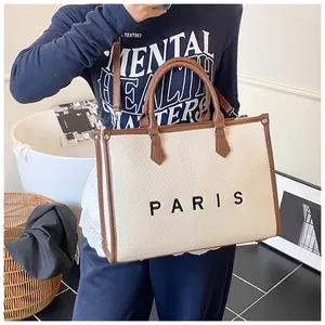 Detailed side view of a large canvas tote bag with PARIS print and brown leather trim
