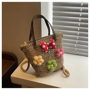 Detail der handgewebten Strandtasche mit Häkelblumen und einer gepunkteten Schleife