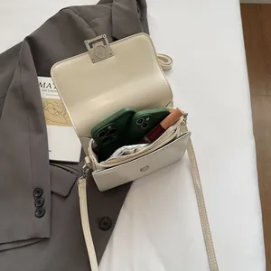 Elegant cream square crossbody bag featuring a sleek silver clasp and dual compartments