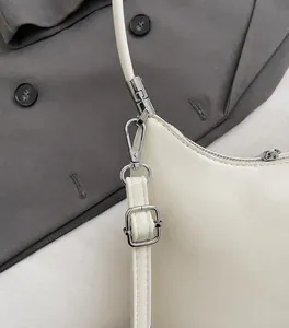 Nahaufnahme der silbernen Metallbeschläge und des cremefarbenen PU-Leders der Tasche