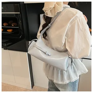 Gros plan d'un sac à bandoulière bleu clair brillant porté par un mannequin en cuisine