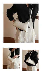 Detail of cream white half-moon hobo bag featuring silver chain and round pendant charm