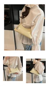 Three-way view of a cream yellow moon-shaped hobo bag with glossy finish and chain detail