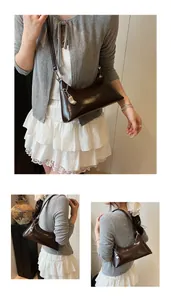 Detail view of glossy brown PU leather underarm bag with elegant silver bean pendant