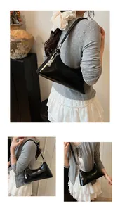 Detail of glossy black PU leather baguette bag with silver zipper and metallic charm