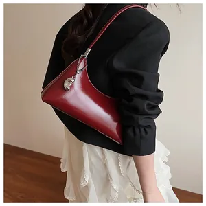 Detail of burgundy patent leather shoulder bag with silver chain and metal pea charm