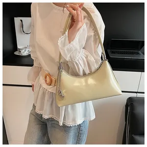 Detail of a creamy yellow glossy PU leather baguette bag with a silver metal chain accessory