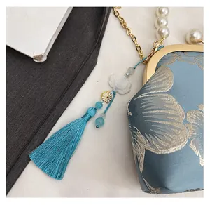 Close-up of blue floral embroidery silk bag with pearl chain handle and silk tassel detail