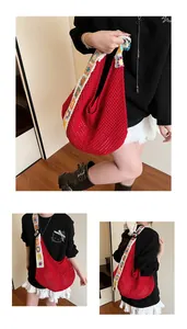 Détail du sac hobo en crochet rouge avec bandoulière fleurie soleil et texture tissée ajourée