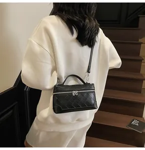 Detail of a quilted black crossbody bag worn by a model on wooden stairs