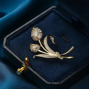 Spilla a tulipano dorata con cristalli bianchi su scatola di gioielli in velluto blu