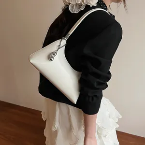 White geometric PU leather shoulder bag with chic silver bean pendant detail shown on model