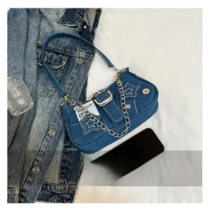 Détails de broderie étoile et chaîne argentée sur un sac porté épaule en jean bleu
