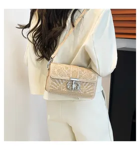 Detail einer beigen Stepptasche mit silbernem Drehverschluss und schmalem Gurt