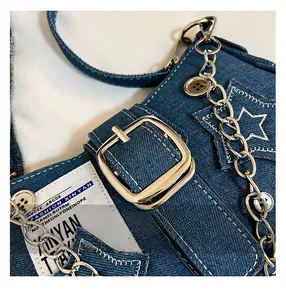 Détail de la broderie étoile et de la chaîne métallique sur le sac bandoulière en denim