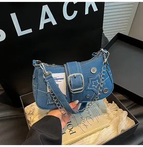 Détail du sac en denim bleu avec étoile et boucle argentée sur emballage cadeau noir