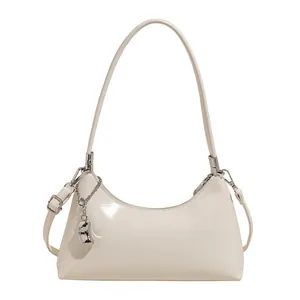 Creamy white hobo bag in glossy PU leather with adjustable crossbody strap and metal charm