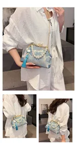Detail of light blue jacquard clutch with gold flower embroidery and pearl handle