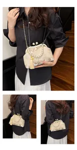 Detail of vintage floral embroidery, pearl handle and tassel on white kiss-lock bag