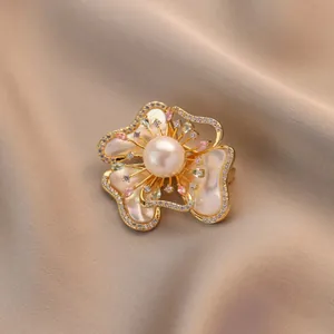 Elegante broche de flor de nácar con perla blanca y cristales sobre fondo de seda