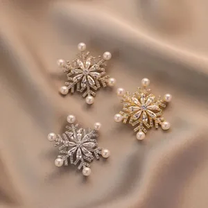 Elegante roterende sneeuwvlok broches met zirkoon en parels op zijden achtergrond