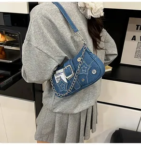 Détail du sac bandoulière en denim bleu avec broderie étoile et chaîne sur un mannequin