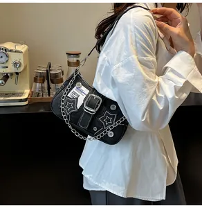Détail du sac bandoulière en denim noir avec broderie étoile blanche et chaîne argentée