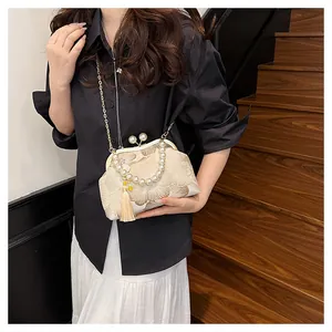 Close-up of beige vintage embroidery bag with pearl handle and floral details