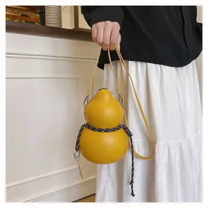 Detailed view of yellow gourd-shaped crossbody bag on model with black and white outfit