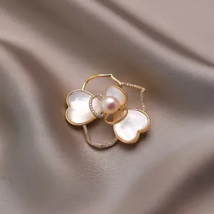 Elegante camelia broche met natuurlijke schelpblaadjes en een parel op een zijden achtergrond