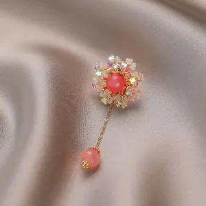 Exquisite floral brooch with pink gemstone and iridescent petals on silk background