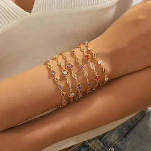 Dettaglio di bracciali dorati a strati con cristalli viola e rossi a forma di cuore